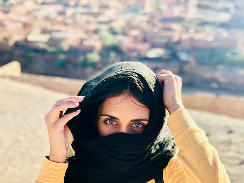 Woman traveler exploring Morocco with a scarf overlooking a Moroccan city